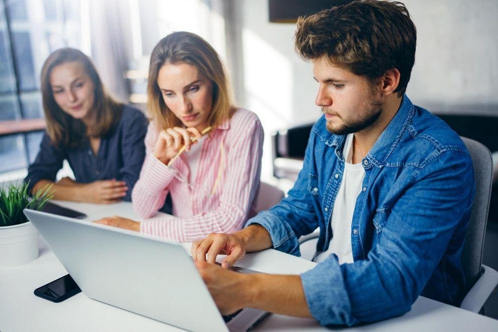 Digitale Gruppenarbeit mit drei Studierenden vor Laptop