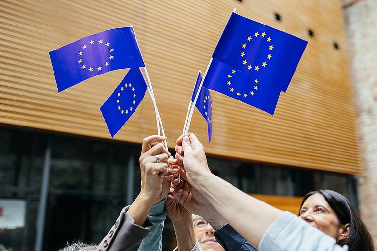 Menschen halten Europa-Flaggen hoch