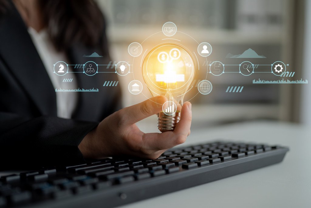 Symbolisches Bild für eine Umfrage zu Webinarthemen. Es wird eine leuchtende Glühbirne über einer Tastatur in der Hand gehalten und seitlich ist bis die Sillhoute einer Frau zu sehen.