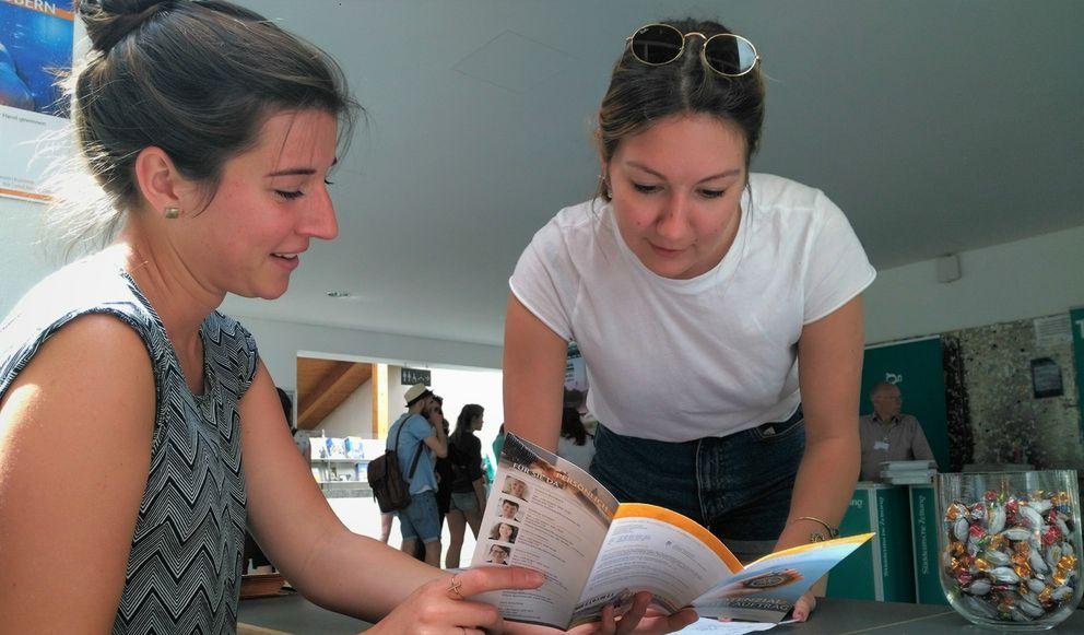 Eine Mitarbeiterin des ZKK berät eine Studentin am Stand in der Mensa