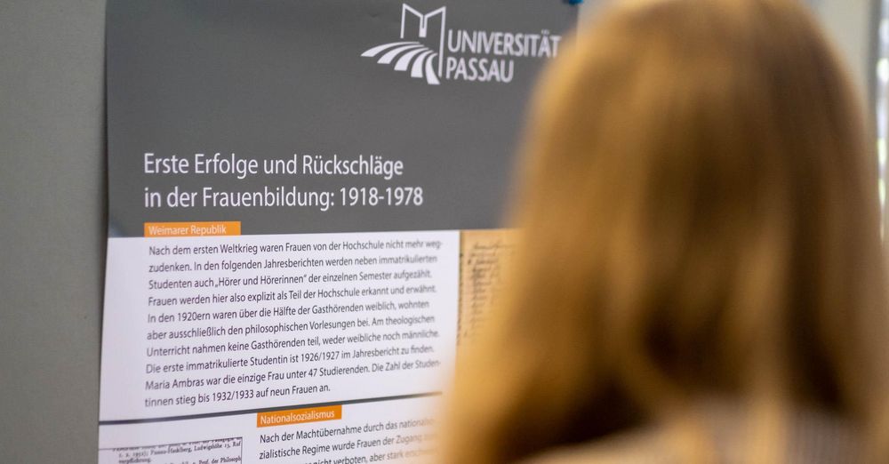 Frau steht vor Plakat zur Ausstellung „Akademische Bildung von Frauen in Passau 1622 bis 2022“