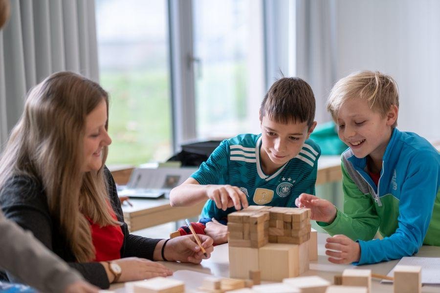 Eine Dozentin und zwei Schüler beim Tüfteln