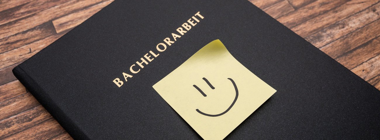 Ansicht einer fertigen Bachelorarbeit, schwarze Hardcoverbindung mit Smiley als Post-it auf der Vorderseite