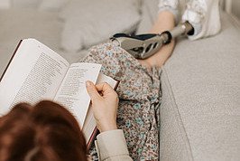 Eine Person liest ein Buch auf einem Sofa