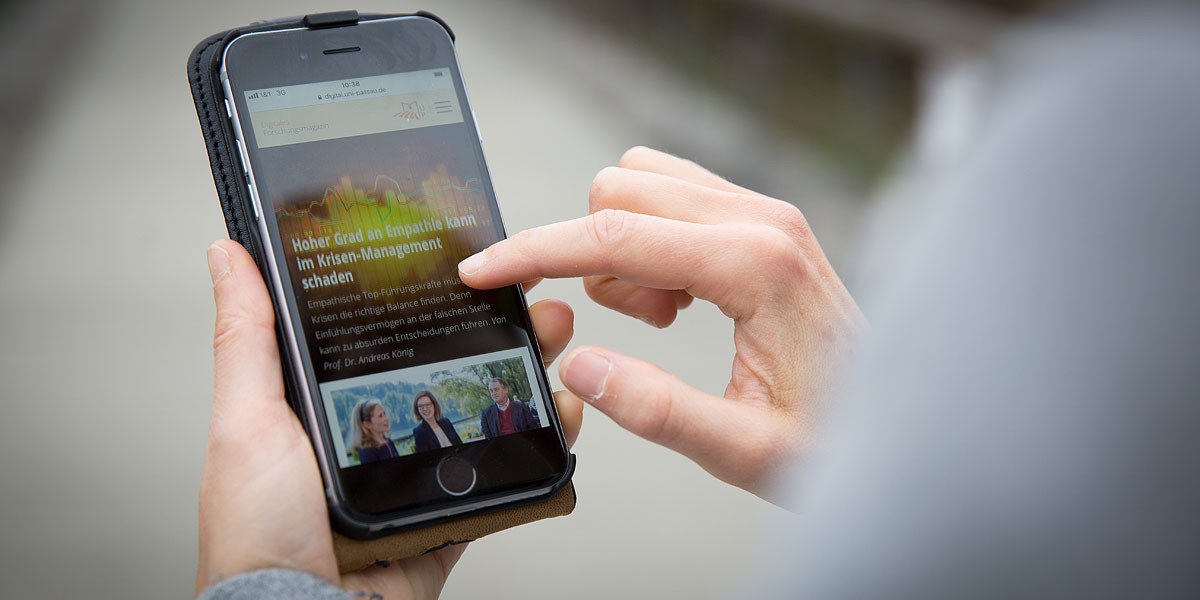 Studierender h&auml;lt ein Smartphone in der Hand