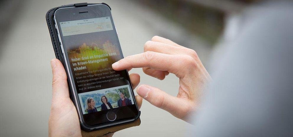 Studierender hält ein Smartphone in der Hand