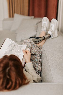 Eine Person liest ein Buch auf einem Sofa
