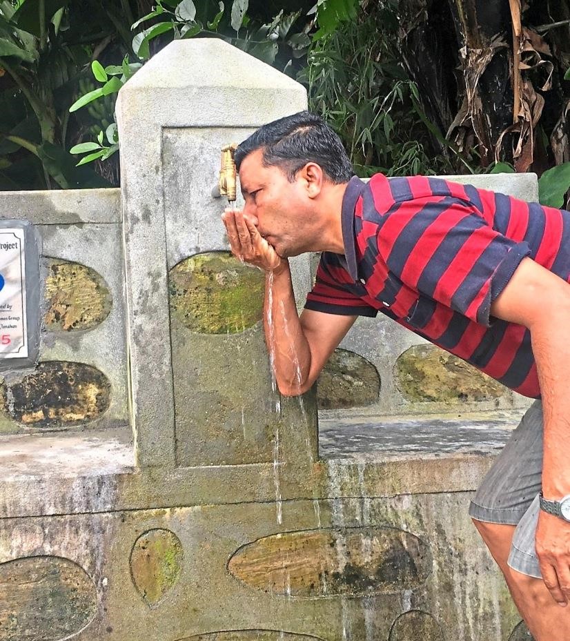 Mann trinkt aus Brunnen in Nepal