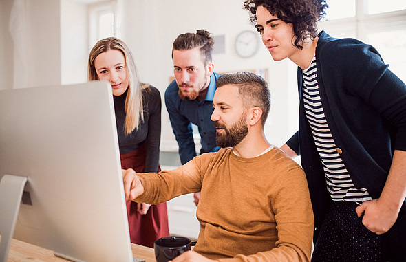 Gruppe junger Menschen, die auf einen Laptop schaut