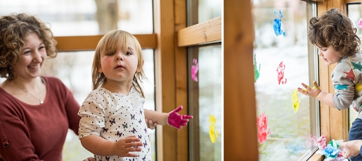 Rainier und Sophia von der Uni-Kinderkrippe "Kr&uuml;melkiste" bringen mit Unterst&uuml;tzung von Erzieherin Sonja mit Fingerfarbe bunte H&auml;nde auf die Fensterscheiben in der Kinderecke