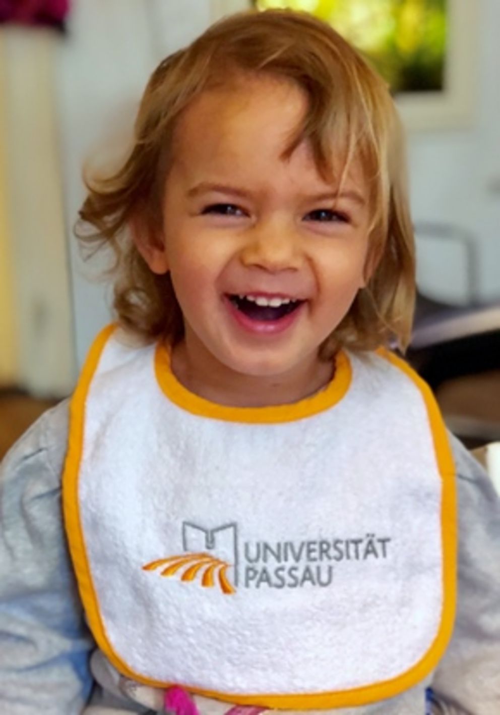 Lachendes Kind mit Universität Passau-Lätzchen