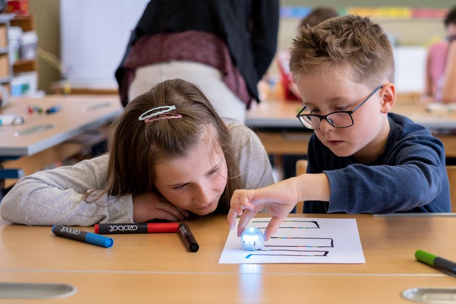 Informatik in der Grundschule: Die Kinder testen gemeinsam mit Prof. Dr. Gordon Fraser den Roboter auf ihrem Blatt Papier.