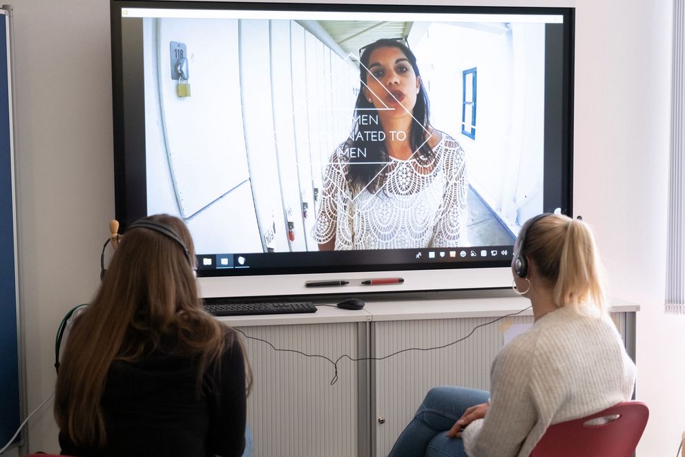 Two women watching the video installation on sexualised violence against women in popular culture