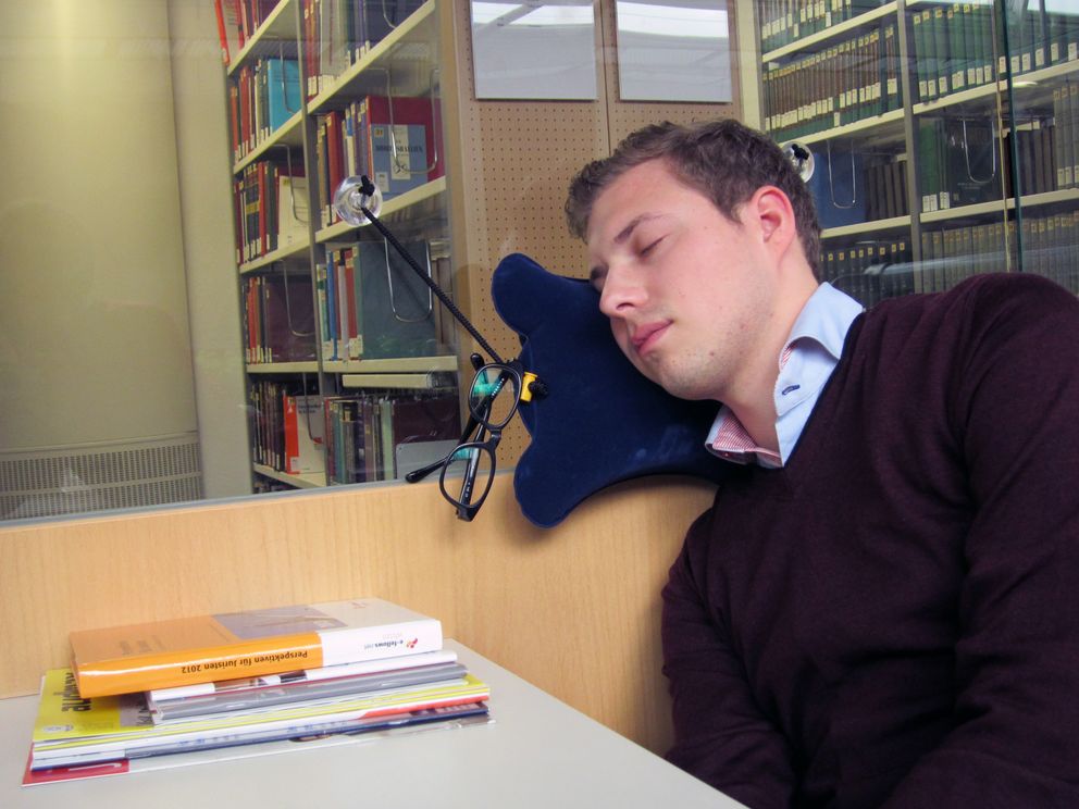 Oliver Voglmaier testet das Kissen „CosySleep“ in der Bibliothek der Universität Passau auf Tauglichkeit für Erholungspausen während der Arbeit an seiner Abschlussarbeit.