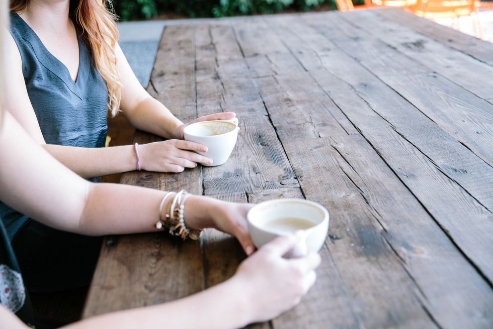 2 Personen sitzen am Tisch mit einer Tasse Kaffee