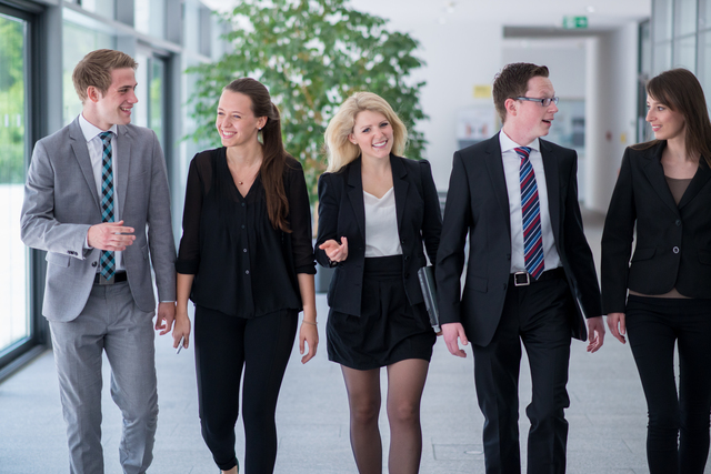 Studierende laufen einen Gang entlang und unterhalten sich angeregt